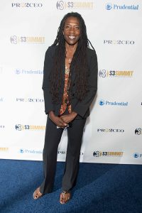 A man with long dreadlocks standing on the red carpet.